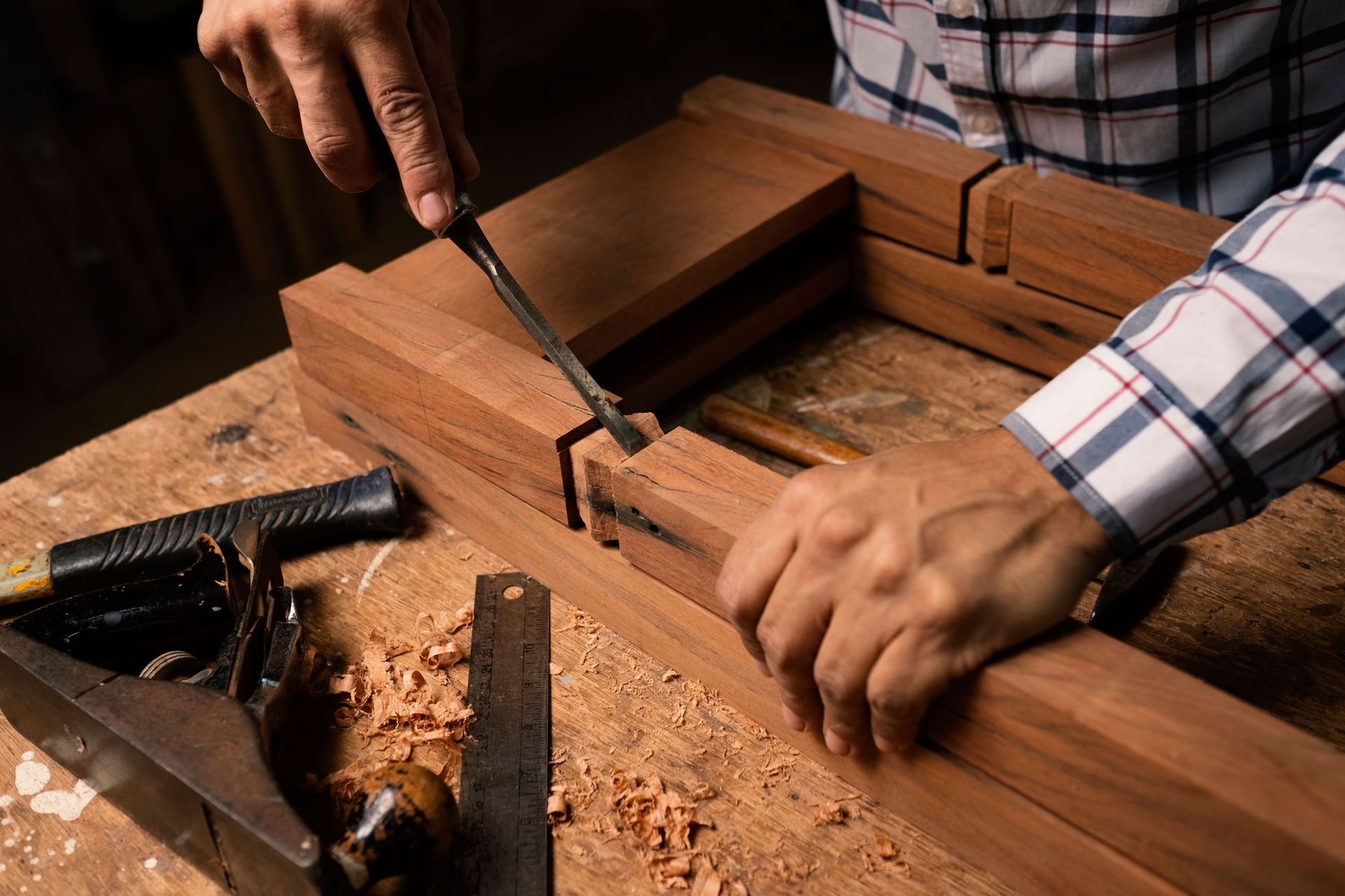Detailed view of hands using a chisel in woodworking, creating precise craftsmanship.
